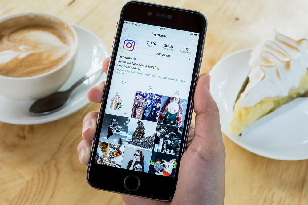 mao masculina segurando smartphone com perfil do aplicativo instagram em tela
