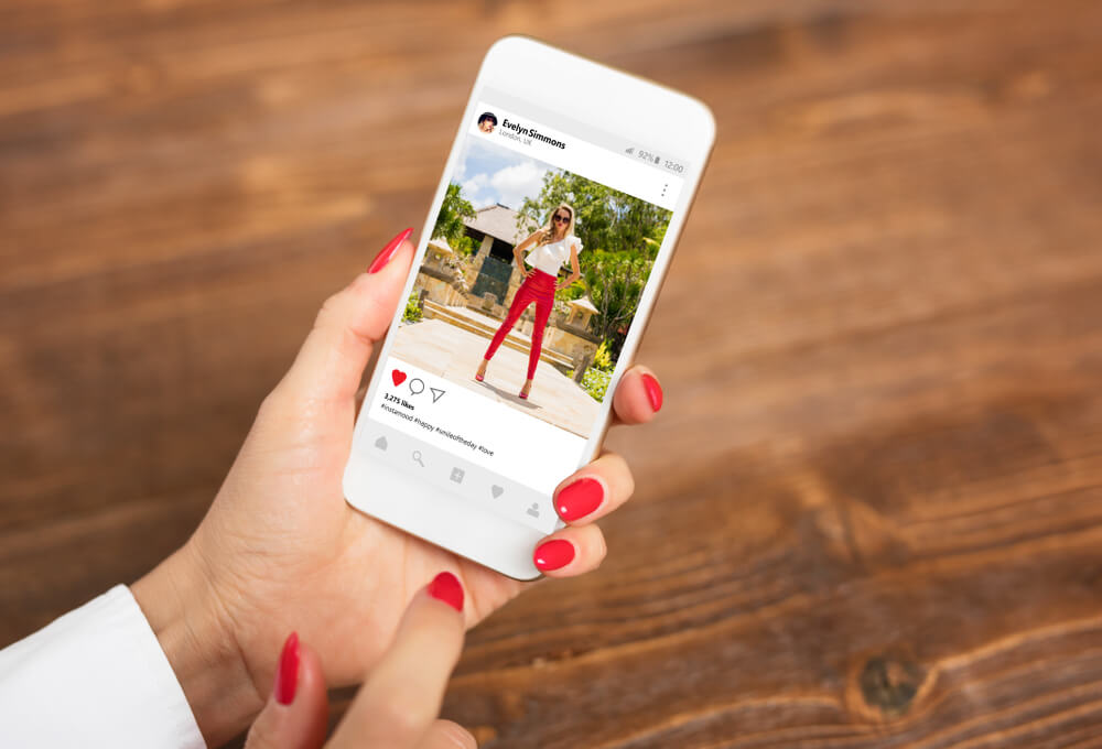 maos fermininas segurando smartphone em publicaçao do aplicativo instagram