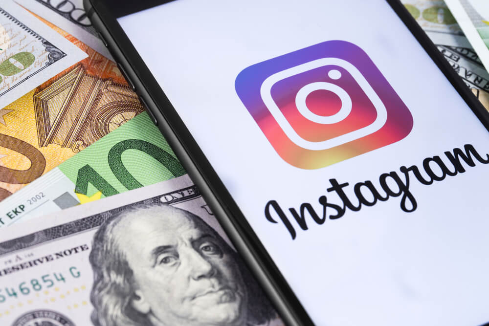 tela de smartphone com icone do aplicativo instagram em tela  e notas de dinheiro ao fundo