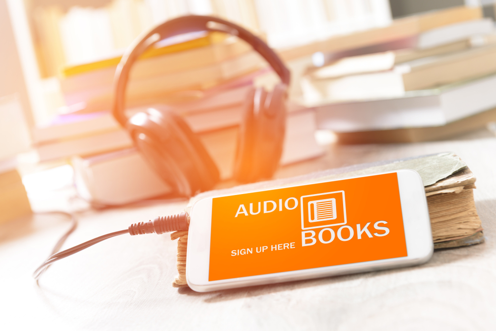 smartphone com acesso a um livro em audio e fone de ouvido