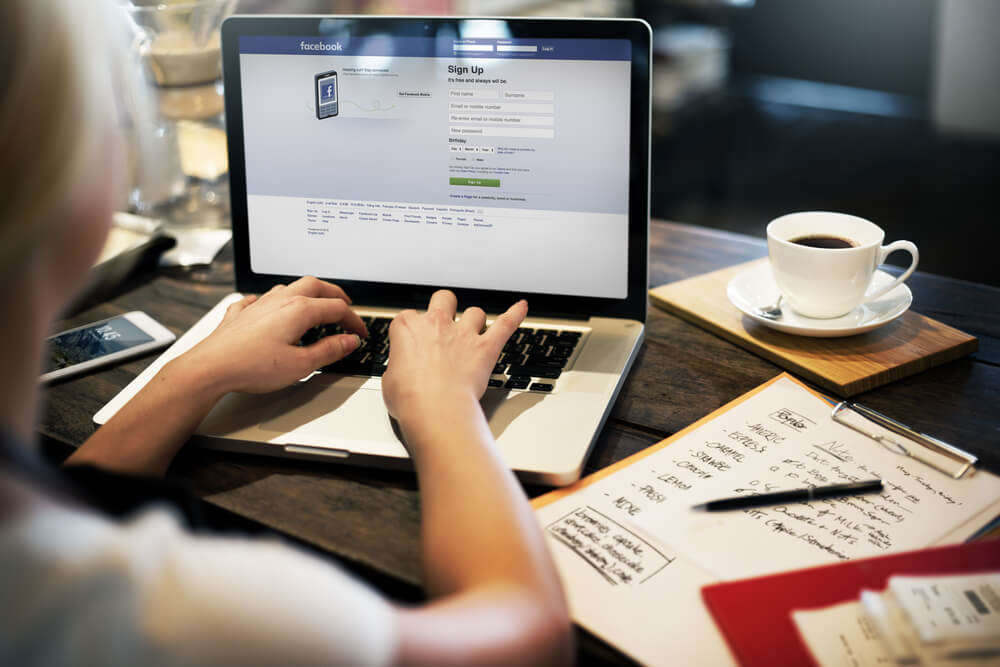 garota em café acessando facebook pelo laptop