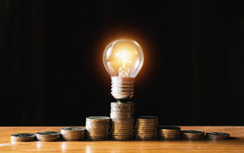lâmpada e montes de moeda representando economia e criatividade
