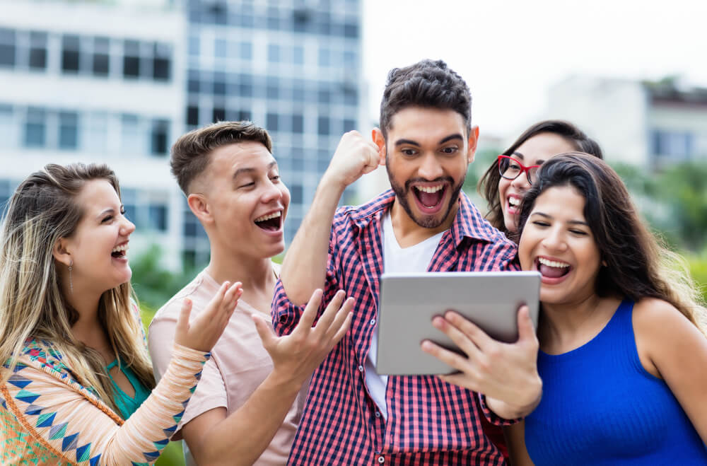 grupo de amigos comemorando vitória em sorteio virtual visto em tablet