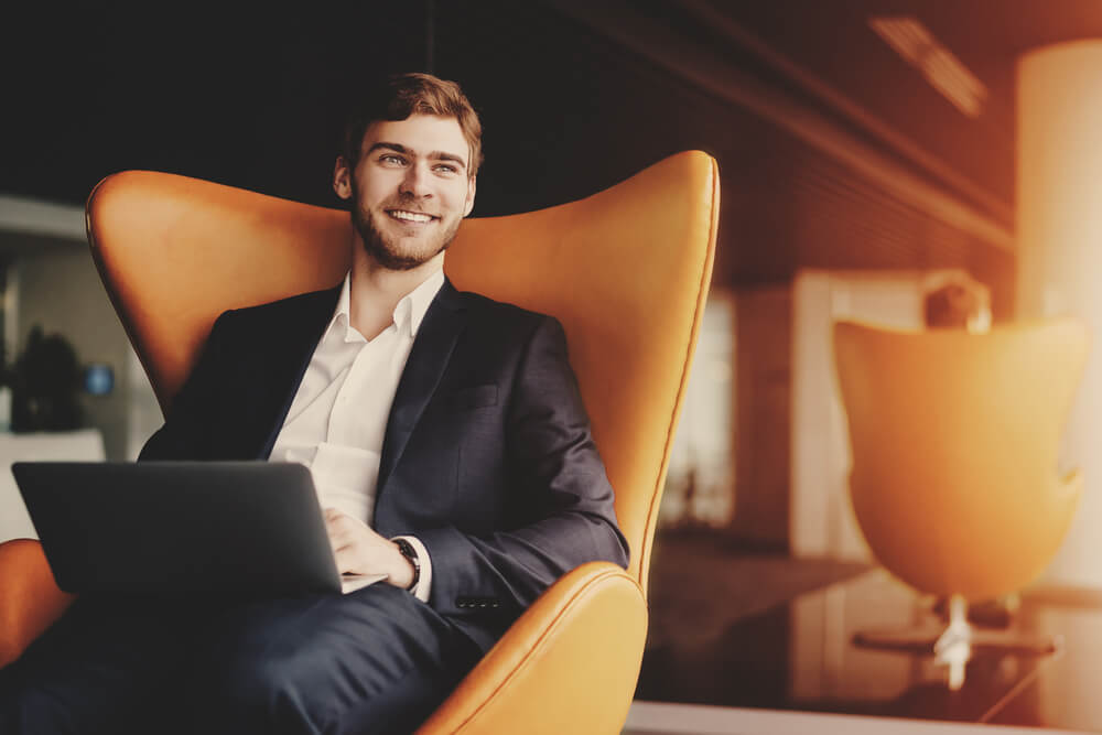 homem empreendedor sorridente sentado em poltrona