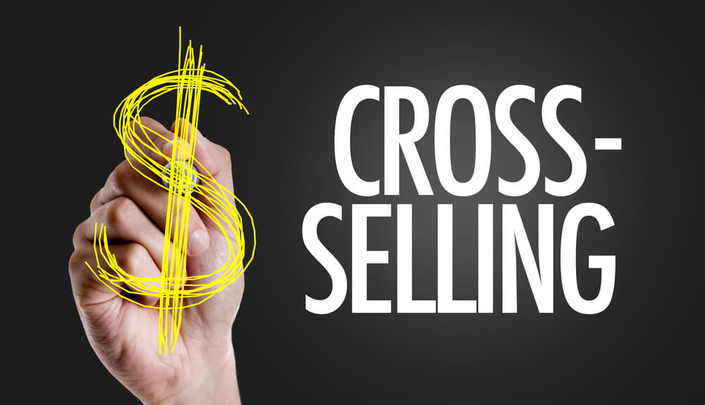 ilustraçao da palavra cross selling com mao desenhando sinal de capital