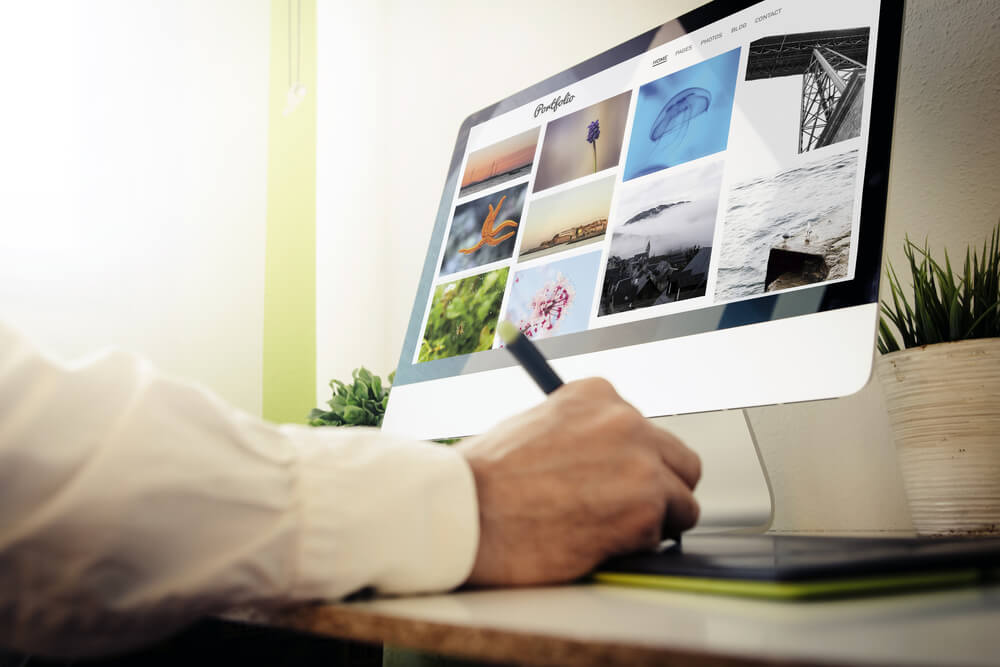 mão masculina em caneta e desktop com tela de acesso a plataforma de portfolio online