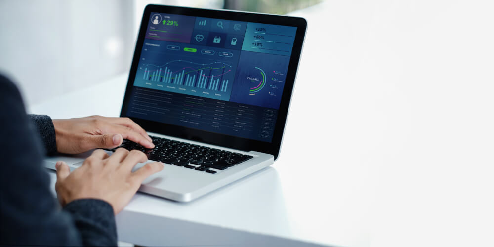 mao masculina em frente a laptop com estatisticas em tela