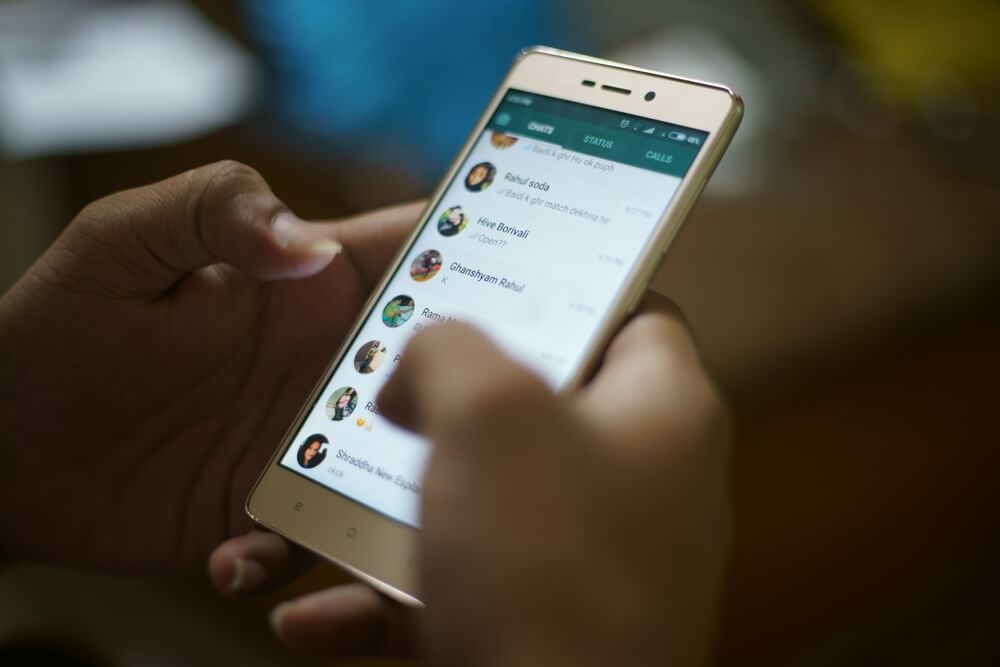 maos segurando smartphone em tela de conversas whatsapp
