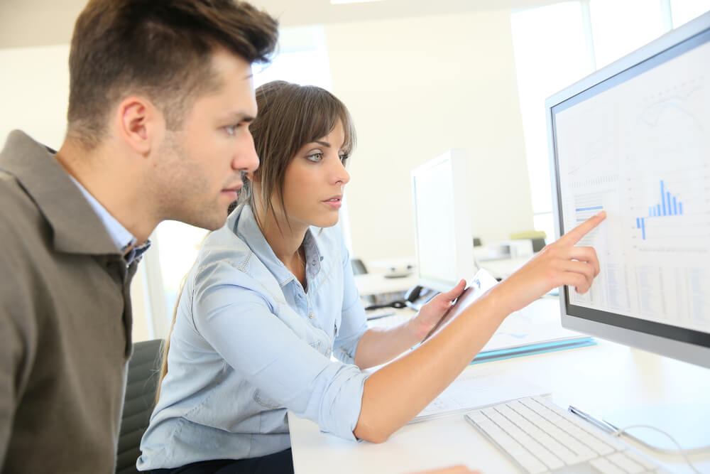 mulher mostrando estatisticas em tela de computador para colega de trabalho