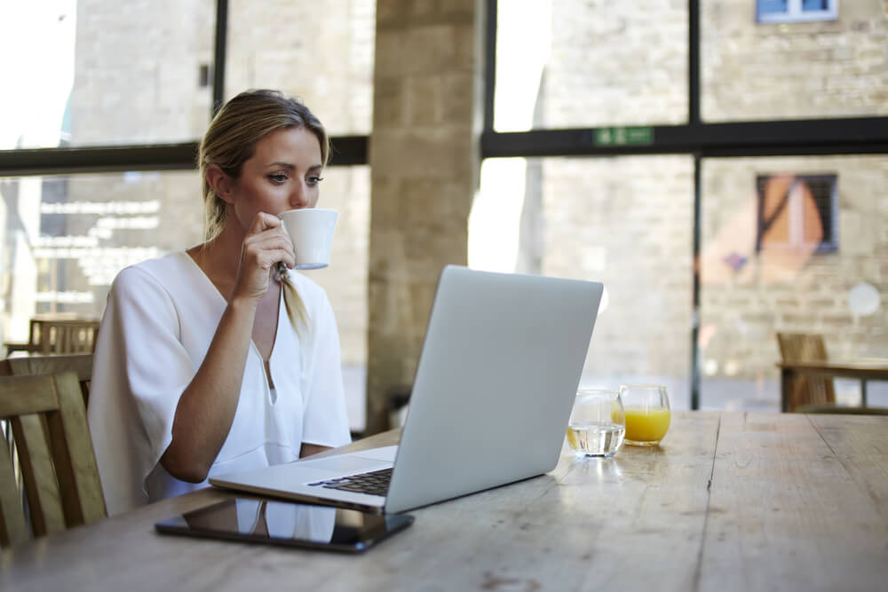 mulher profissional trabalhando remotamente enquanto toma café