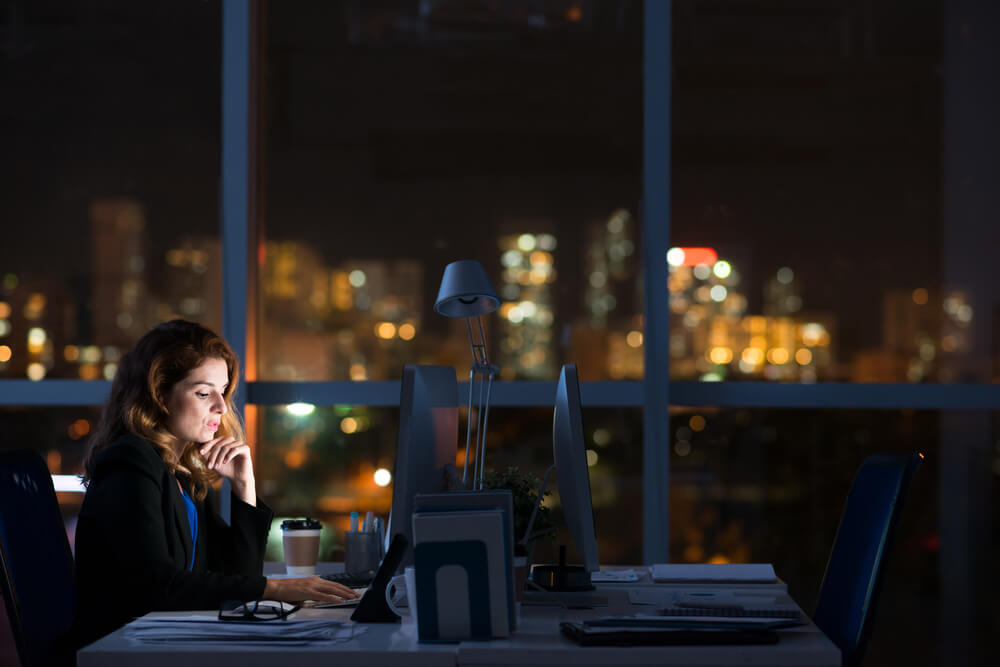 mulher profissional trabalhando sozinha em escritório a noite