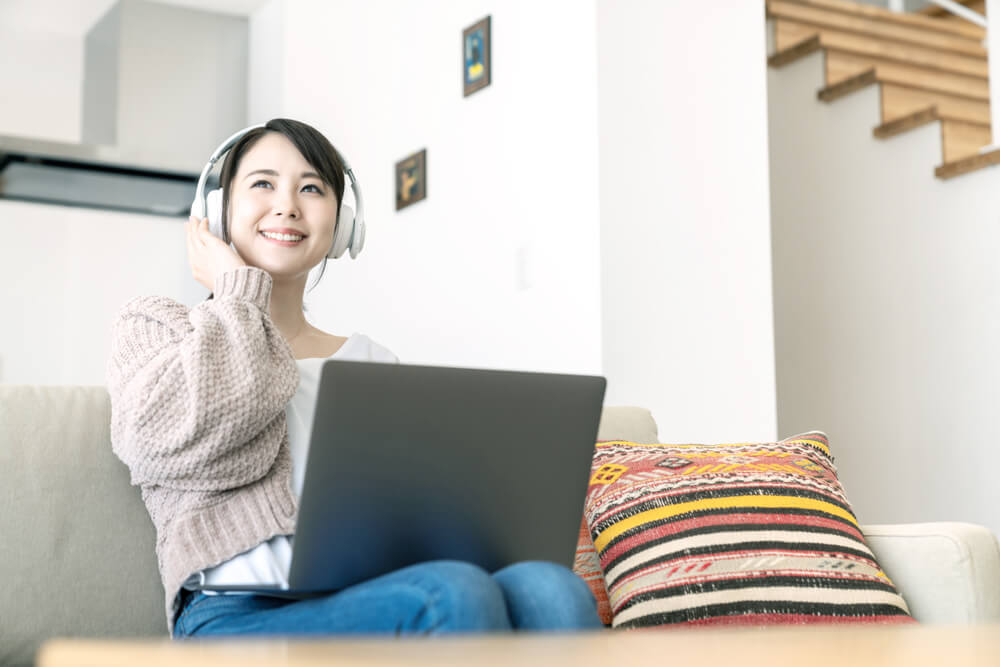 mulher sorridente em frente a laptop e fones de ouvido