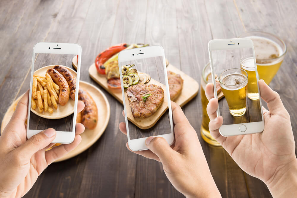 pessoas tirando fotos de comidas e bebidas com smartphones