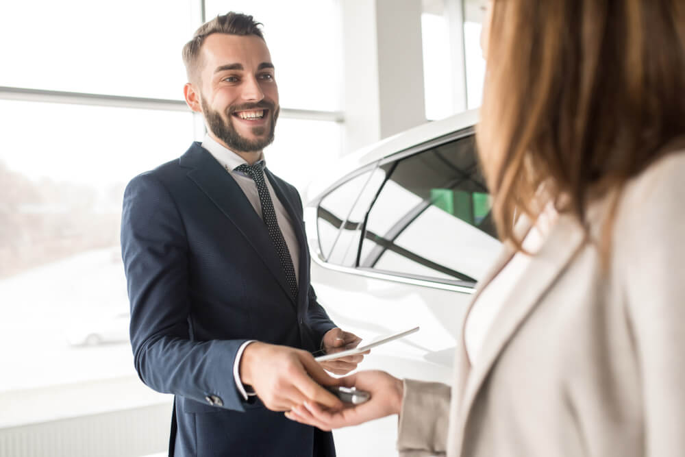 profissional em venda de automoveis exercendo sua profissao ao entregar chaves para cliente