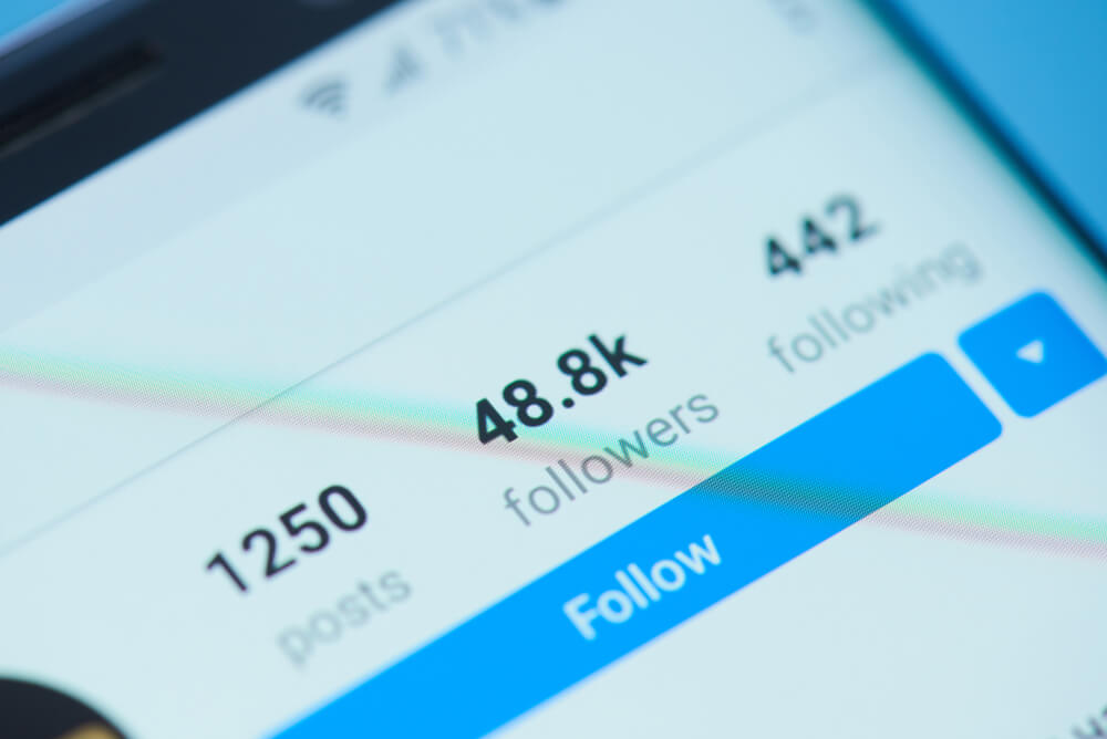 smartphone com perfil do aplicativo instagram mostrando seguidores seguindo e postagens em tela