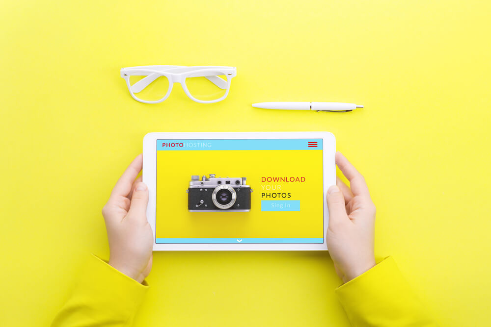 tela amarela com mãos segurando tablet com conteúdos