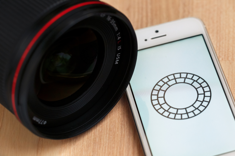 lente de camera ao lado de smartphone com icone de aplicativo VSCO cam em tela
