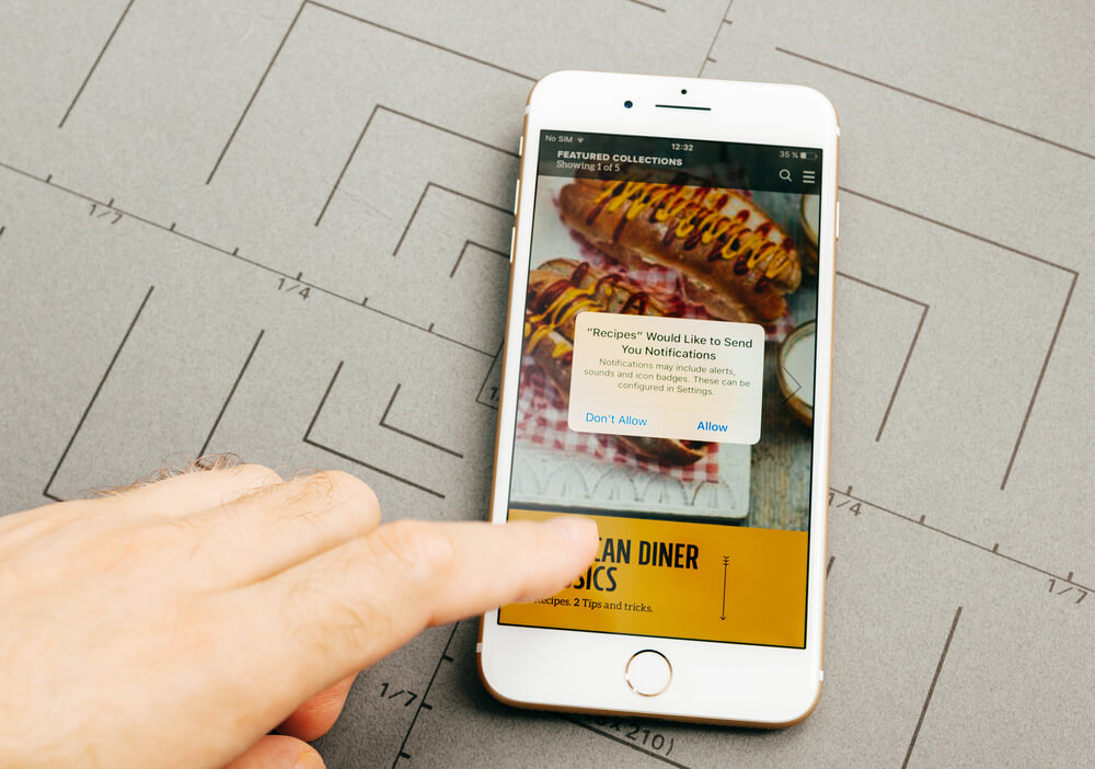 mão masculina indicando smartphone com aplicativo de refeições em tela