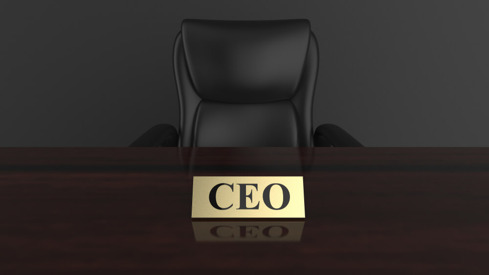 cadeira executiva atras de mesa com cracha sob a mesma com a palavra CEO
