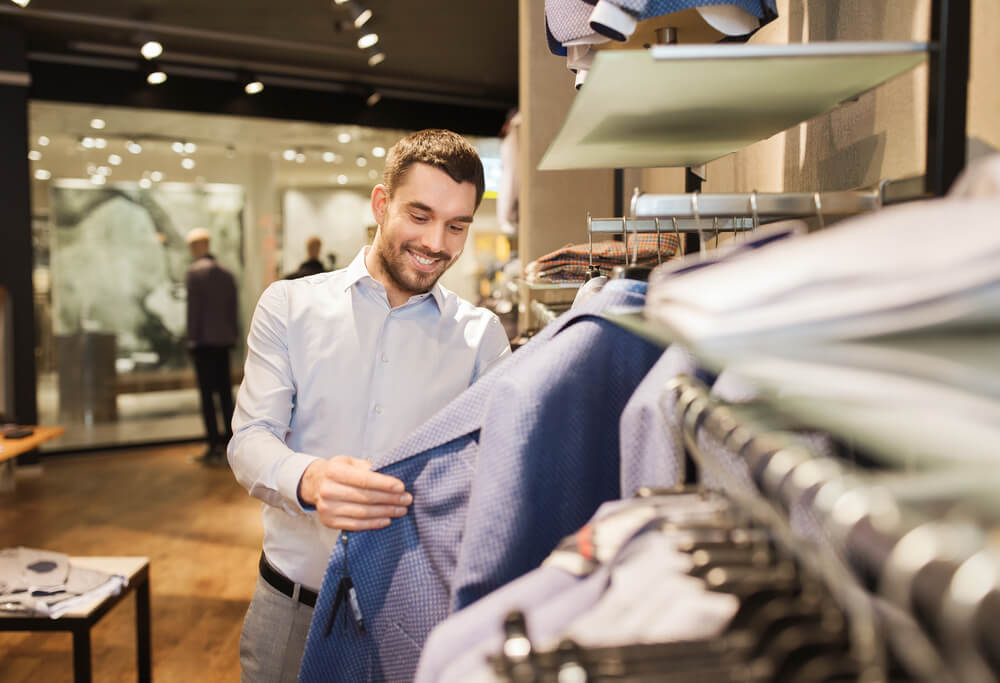 consumidor otimista sorrindo ao escolher roupa em loja