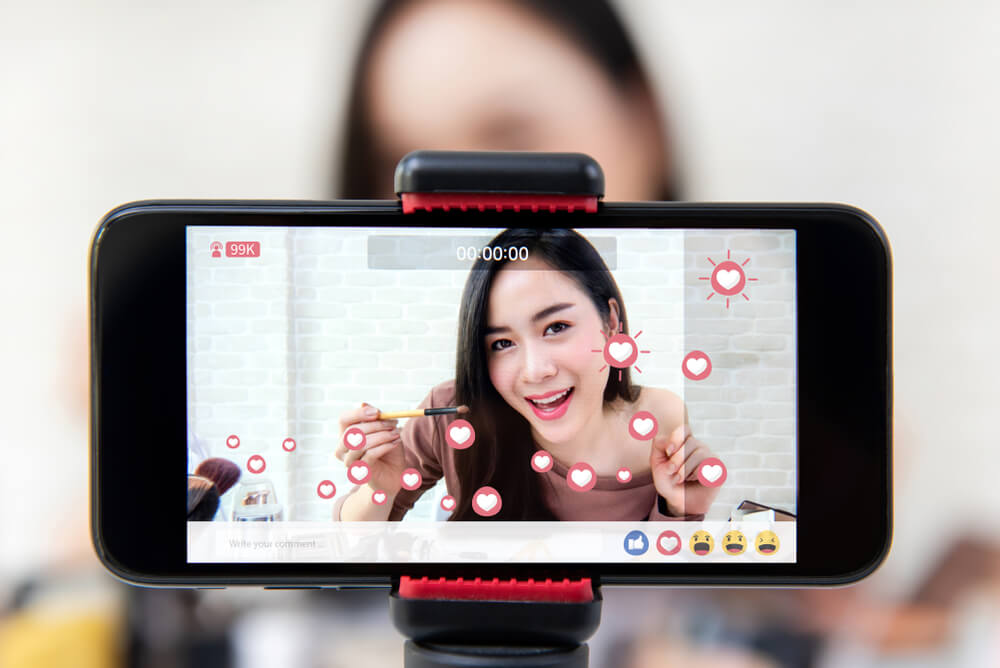 smartphone gravando mulher em meio a live de rede social mostrando produtos de beleza