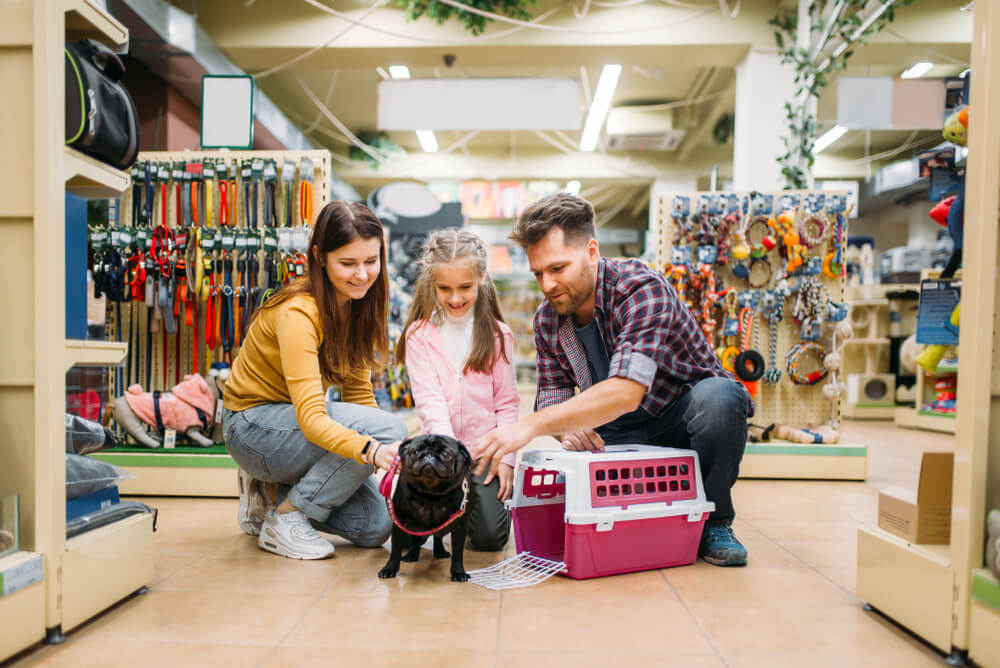 familia com seu cachorro escolhendo caixa transporte em pet shop