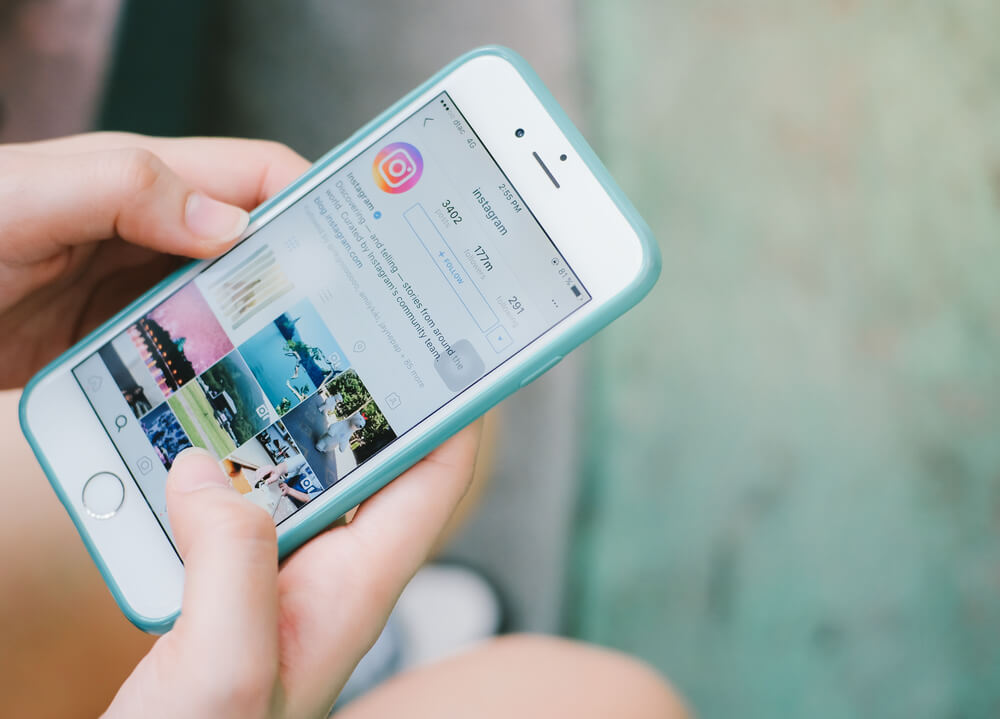 maos segurando smartphone com perfil do aplicativo instagram em tela