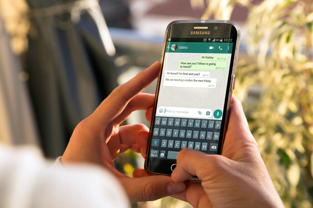 maos segurando smartphone com conversa do aplicativo whatsapp em tela